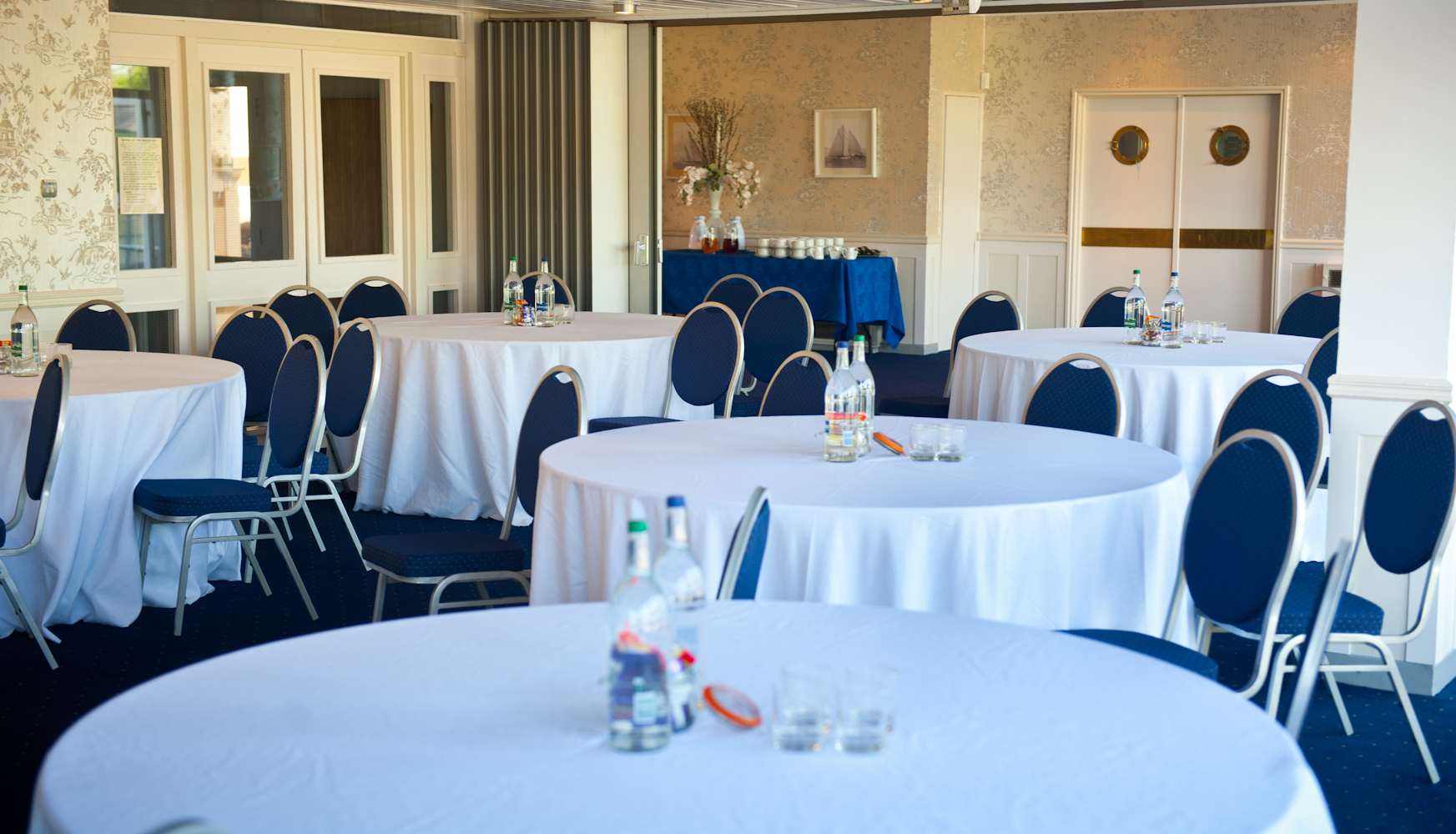 Thames Suite event space with round tables, blue chairs for meetings or gatherings.