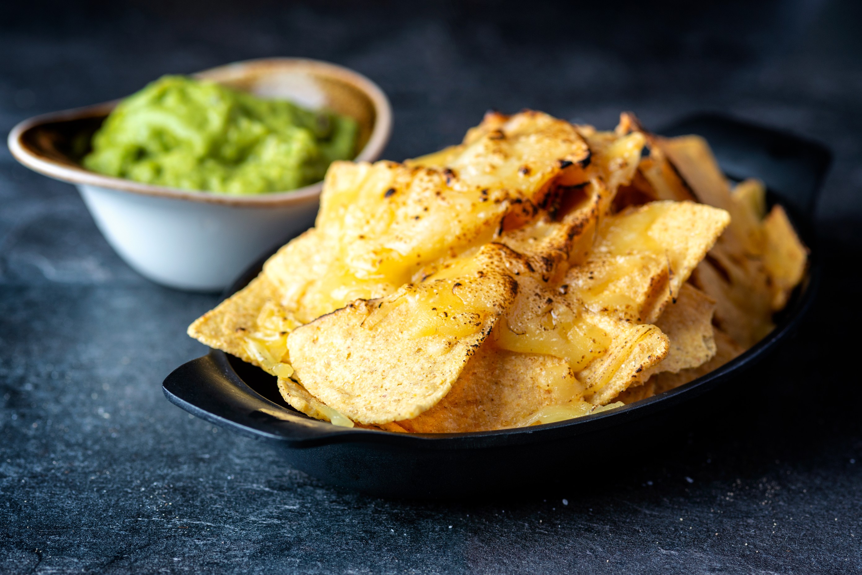 Vibrant nacho platter with cheese and guacamole at TwoRuba Bar, Hilton London Tower Bridge.