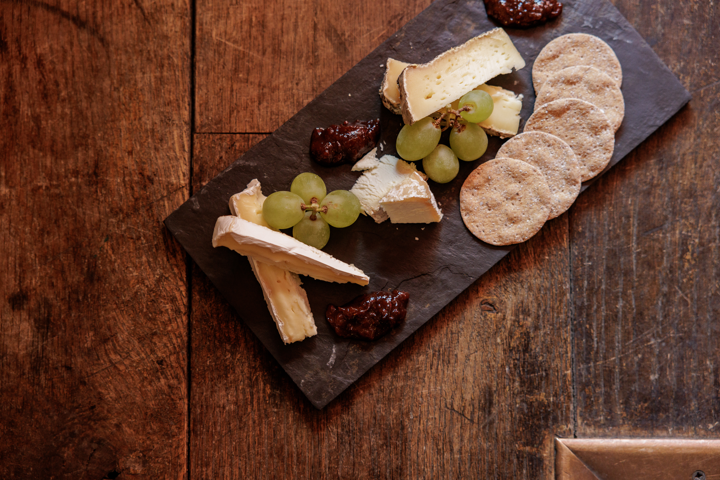 Cheese platter on slate board for networking event in The Crypt, featuring grapes and crackers.