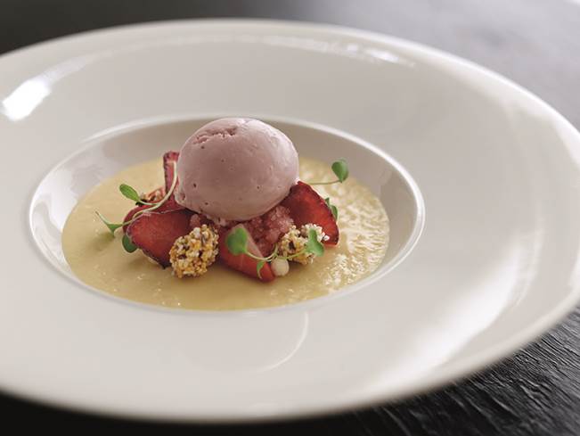 Lavender ice cream dessert with strawberries at upscale dining event.