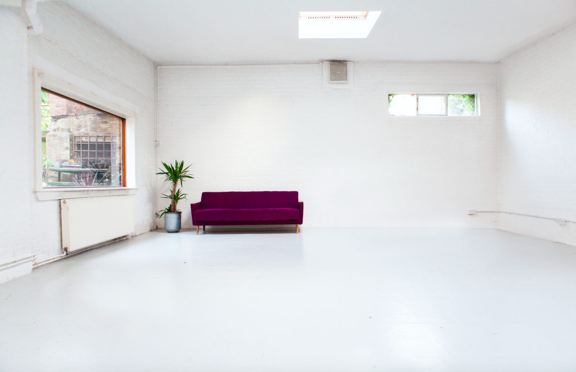 Minimalist event space with purple sofa, ideal for workshops and meetings.