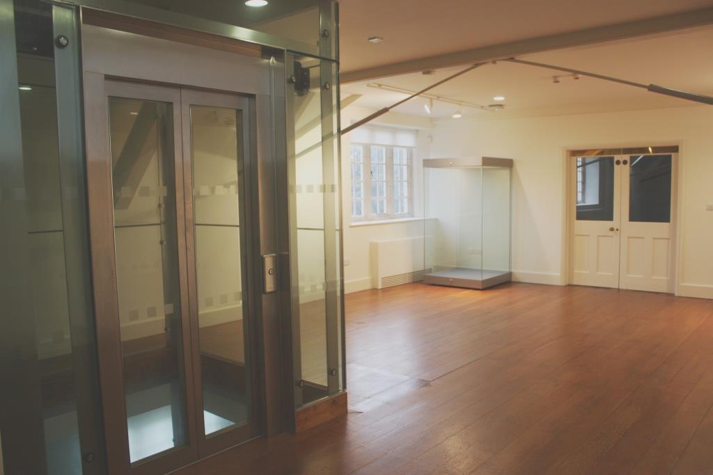 Alt text: Modern glass event space with wooden flooring at The Stables, Aston Hall.