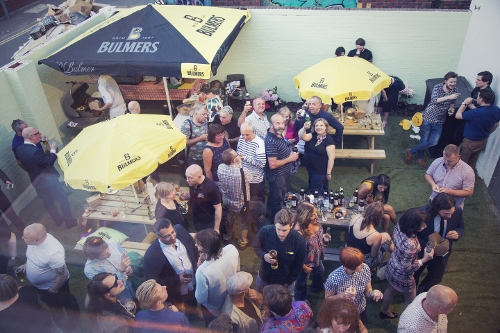 Vibrant outdoor networking event at The Night Owl with branded umbrellas and food stations.