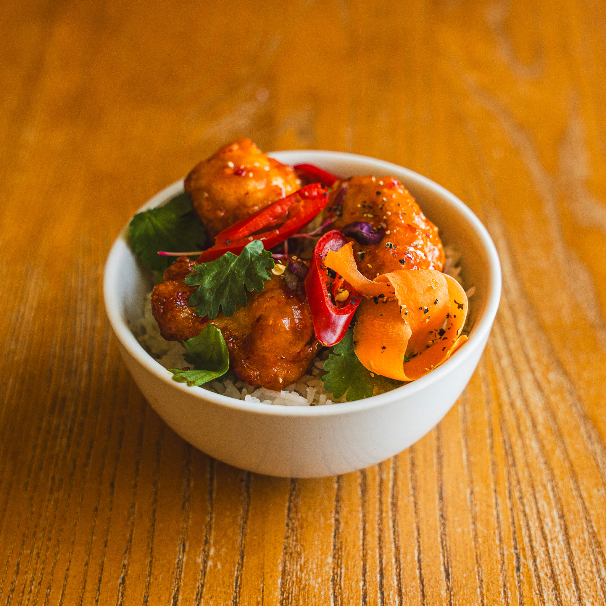 Crispy chicken dish in vibrant sauce at Chessington World of Adventures catering event.