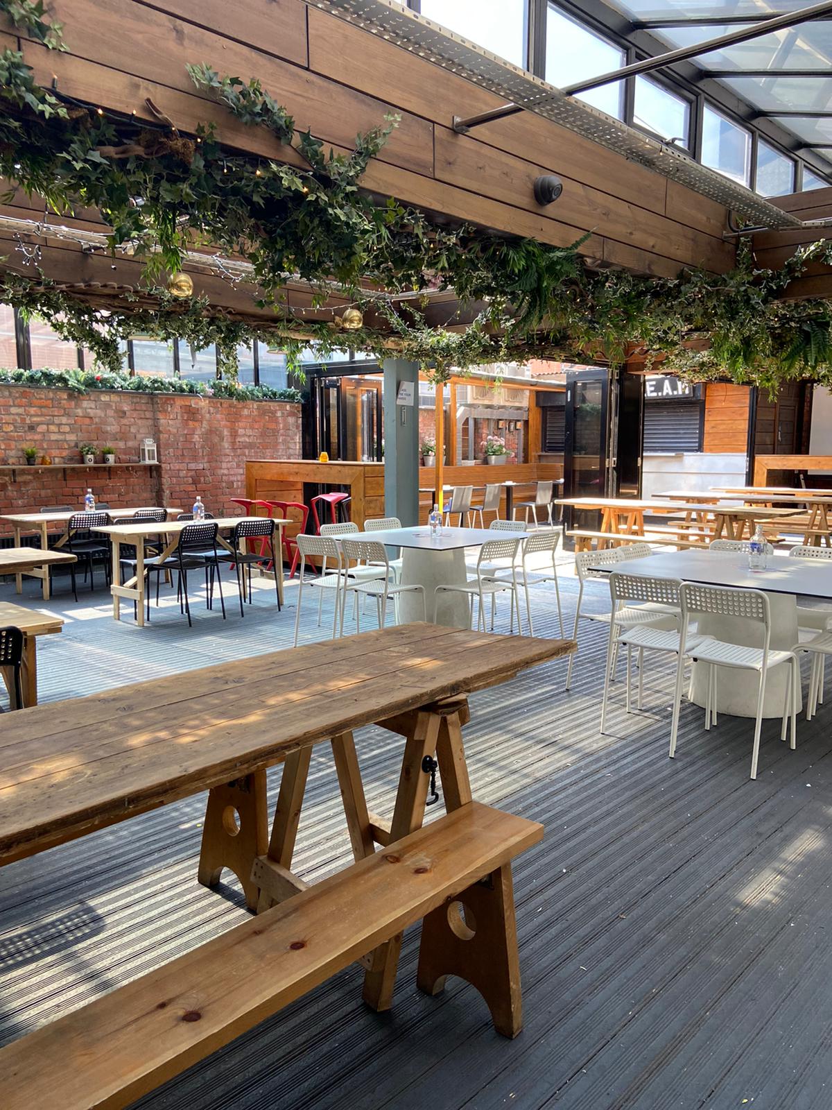 Outdoor event space at The Greenhouse, featuring greenery and flexible seating arrangements.