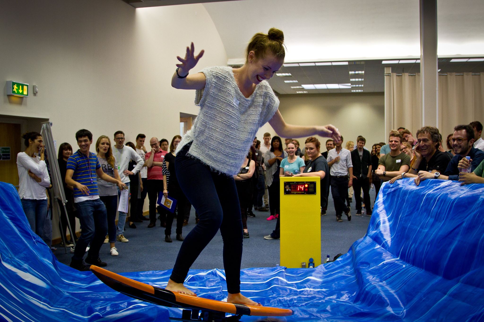 "Participant surfing on wave simulator at Thames Hall, Oxford for team-building event."
