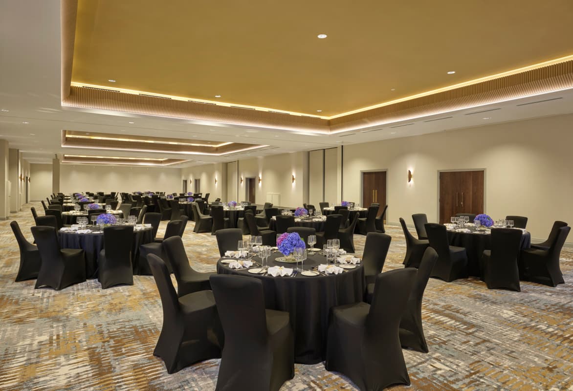 Modern Tower Suite hotel ballroom set for a formal gala banquet with elegant cove lighting.