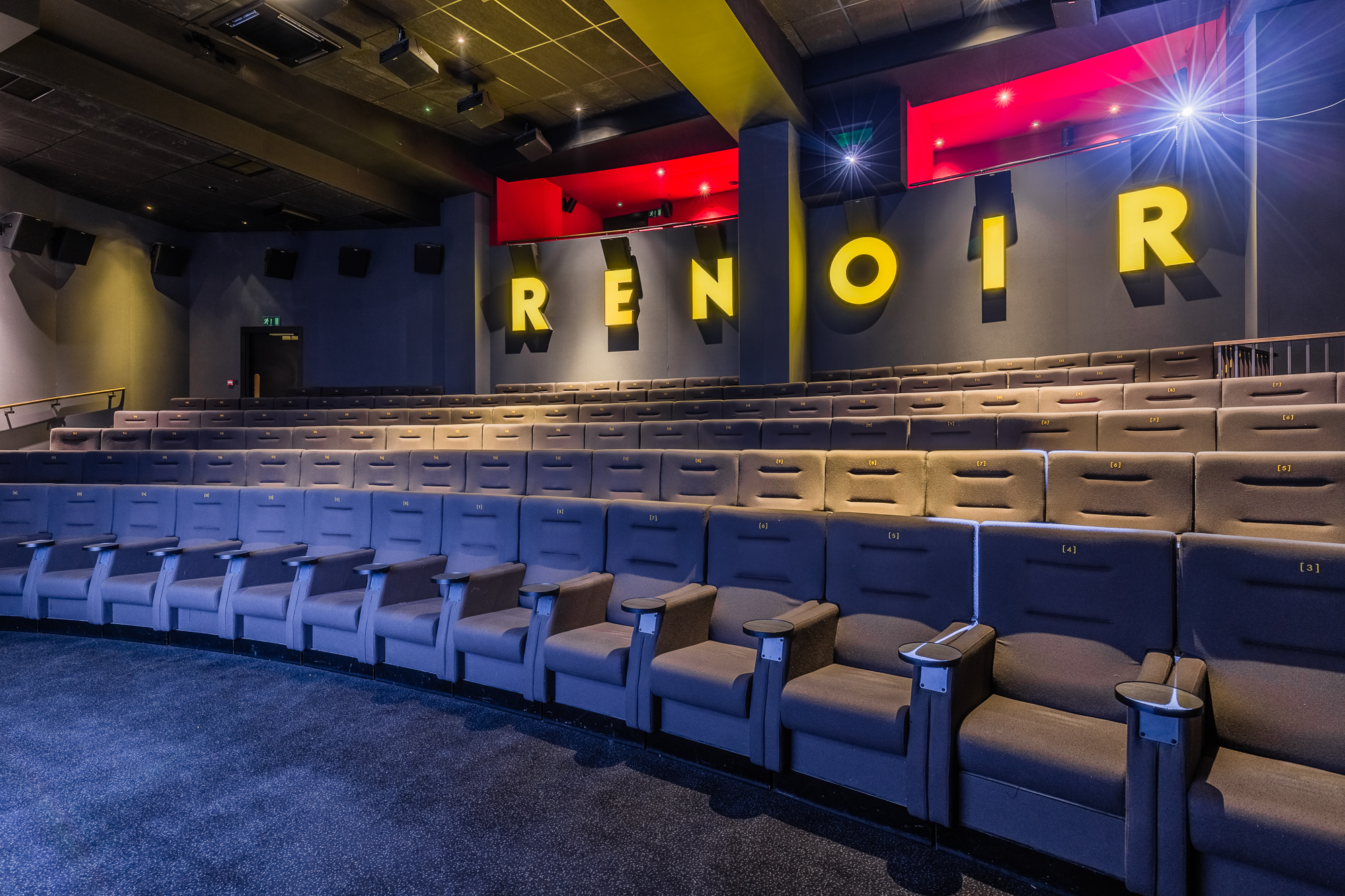Modern theater with plush seating and vibrant lighting for film screenings and presentations.