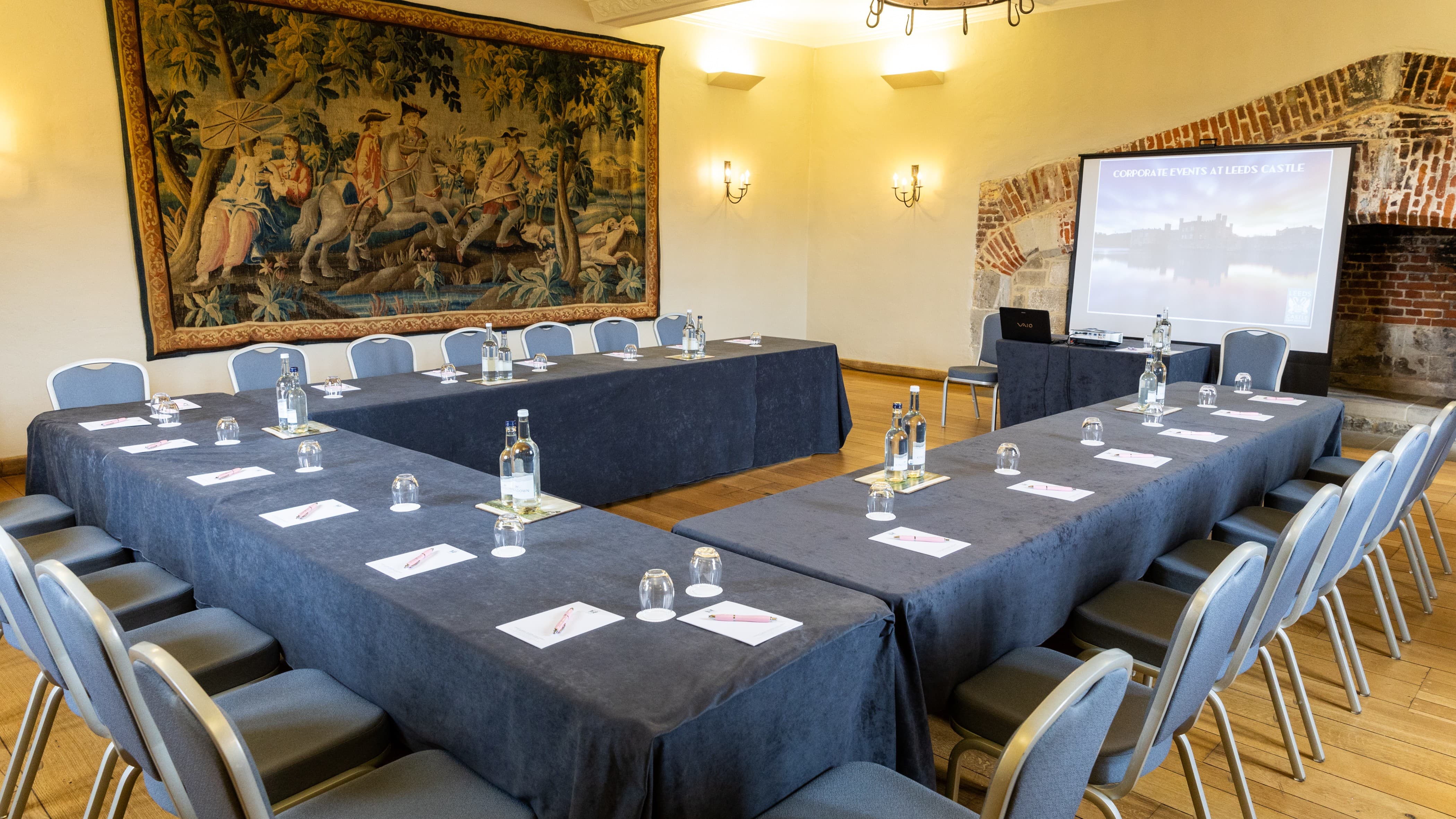 U-shaped conference setup in Leeds Castle’s historic Tudor Hall for professional event meetings.