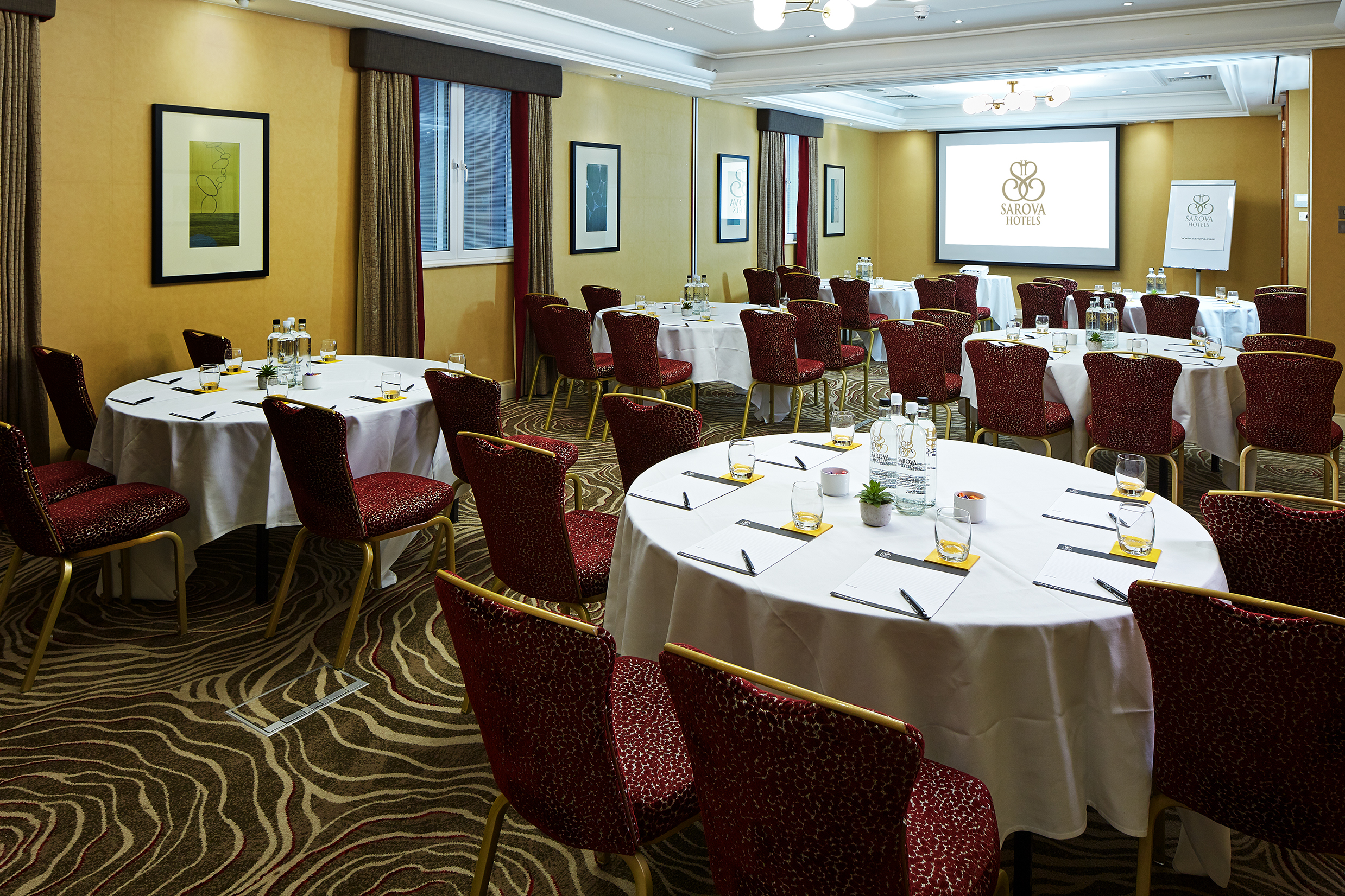 Queens Suite meeting room with circular tables, ideal for professional events and presentations.