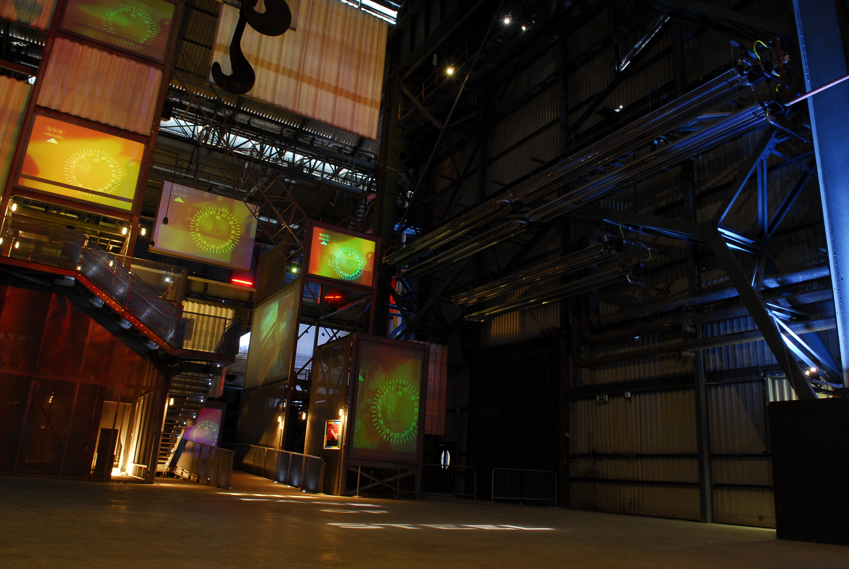 Spacious industrial venue with vibrant projections for corporate events and showcases.