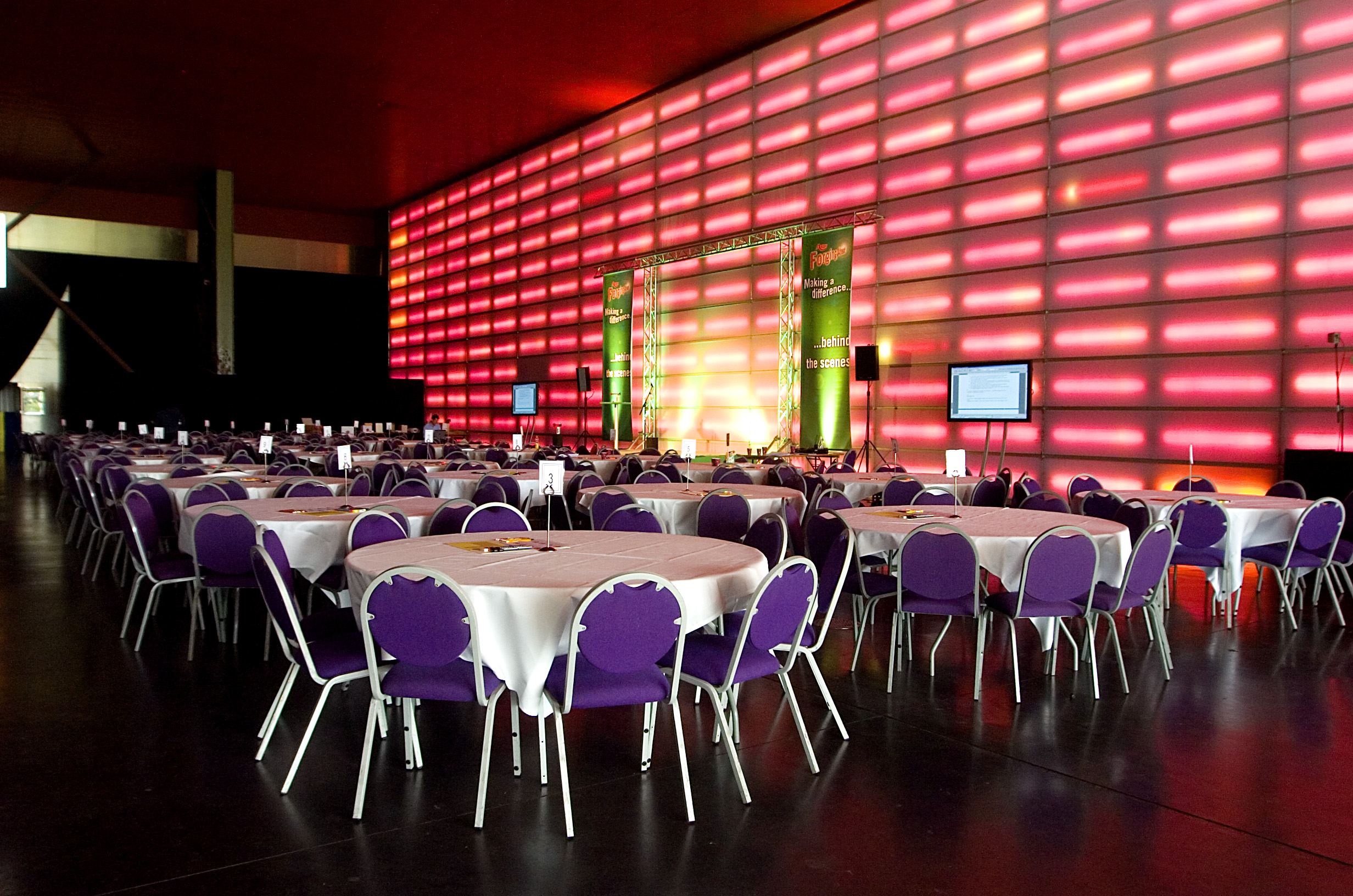 The Red Hall at MAGNA: vibrant event space with round tables and purple chairs.