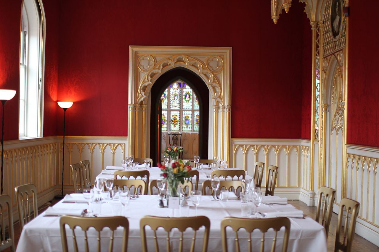 Elegant dining room at Strawberry Hill House, featuring red walls and stained glass for weddings.