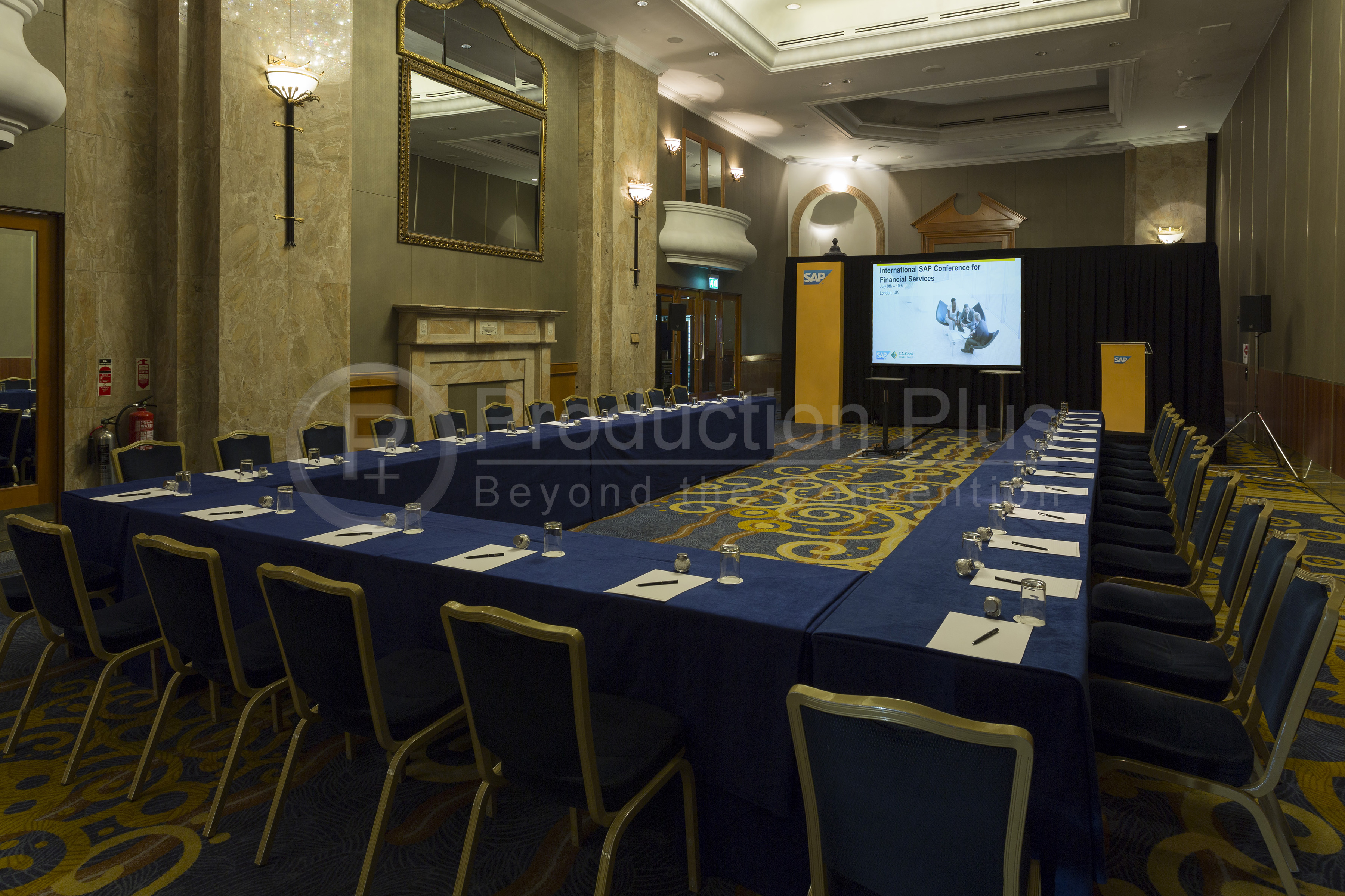 Grand Ballroom at London Hilton: elegant corporate meeting setup with presentation screen.