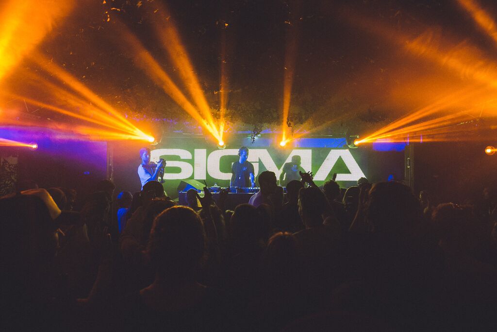 DJ performance at The Bomb Factory, Osea Island, with vibrant lighting and engaged crowd.