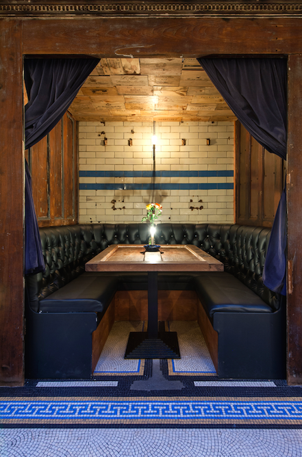Cozy wine bar booth with rustic table, perfect for meetings and gatherings.