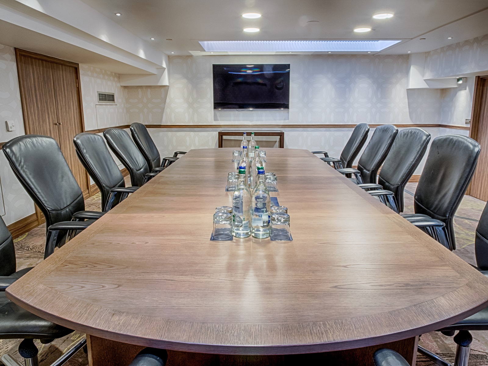 Boardroom 1 at Hilton London Kensington, featuring a long wooden table for corporate meetings.