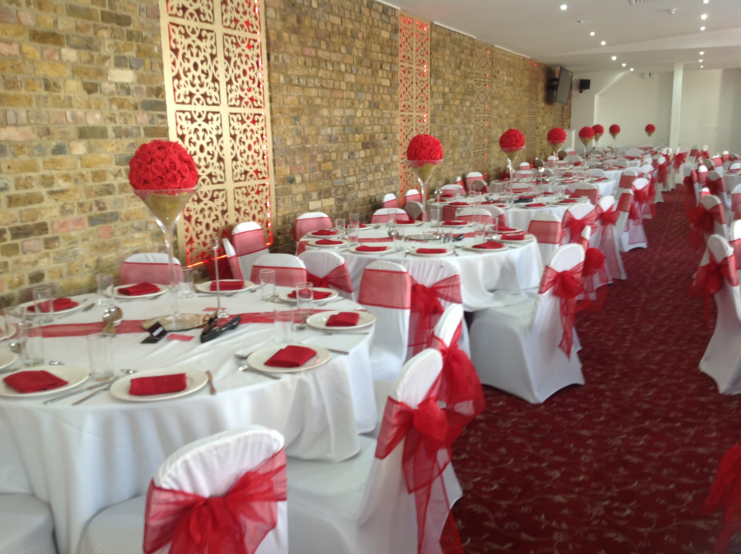 Elegant banquet hall with red floral centerpieces, perfect for weddings and events.