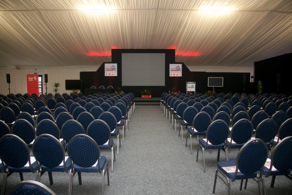 Clive Emson Conference Hall setup for a professional conference with blue chairs and large screen.