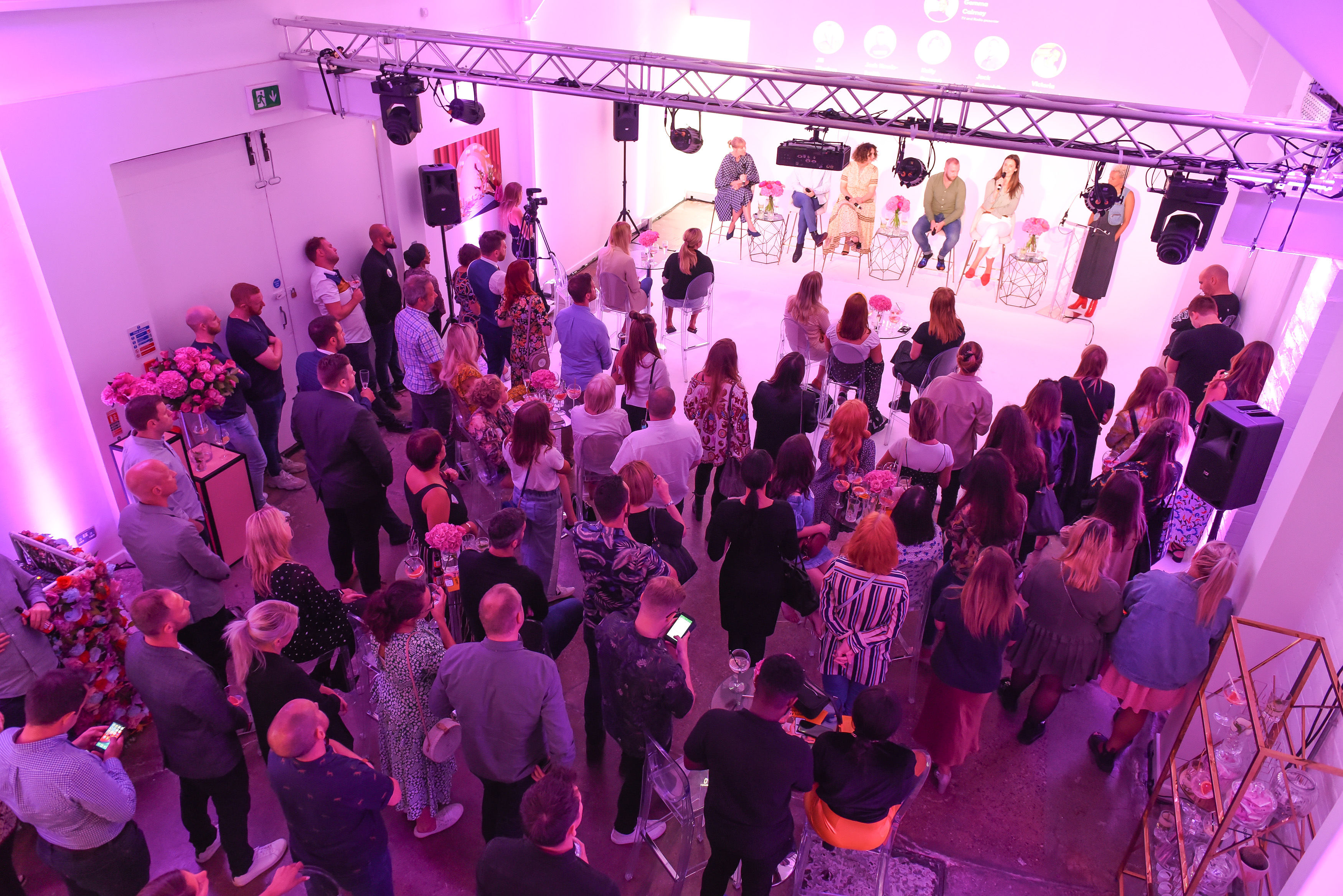 Vibrant panel discussion in well-lit studio with engaged audience and floral decor.