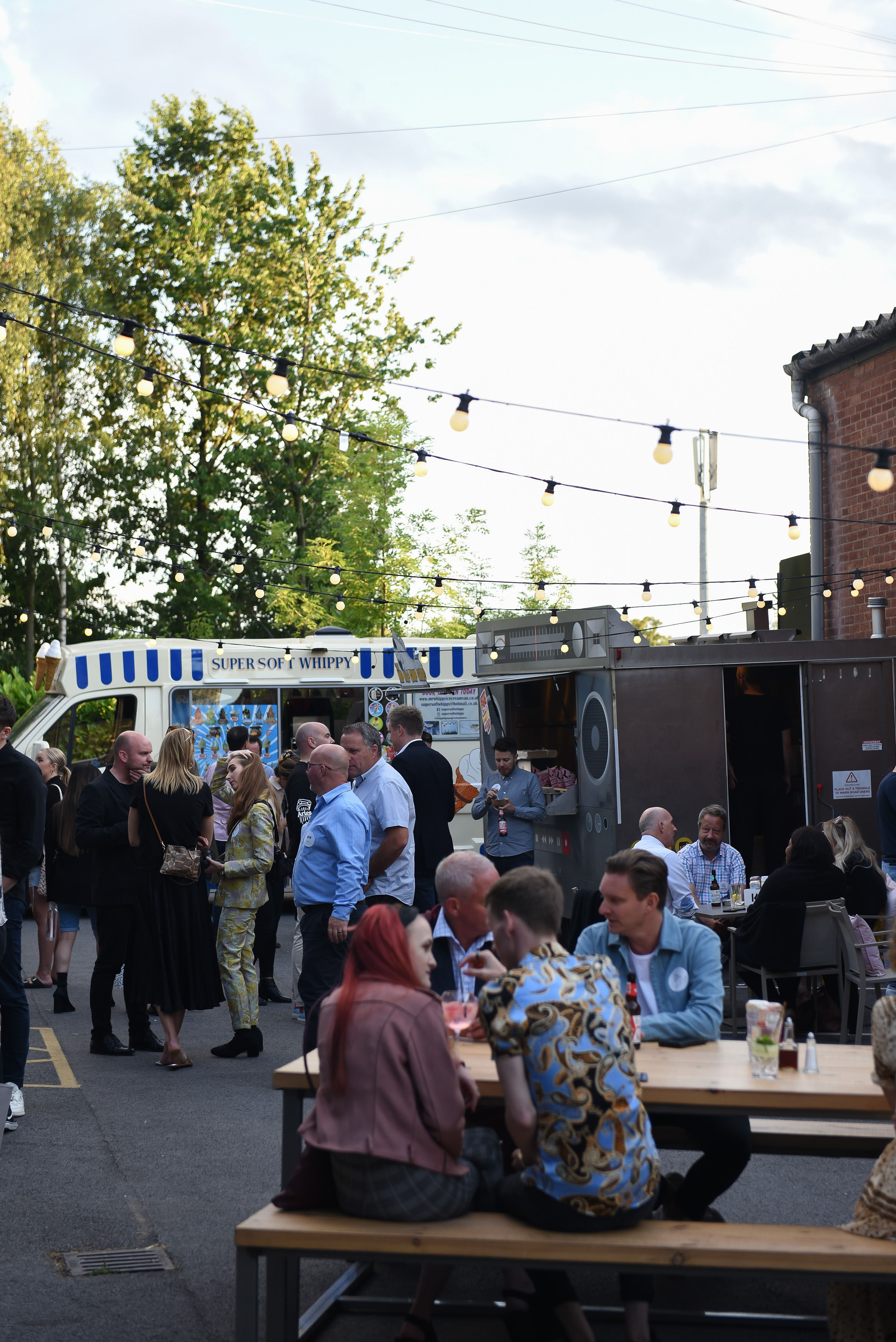 Vibrant outdoor networking event with food trucks and diverse attendees mingling.