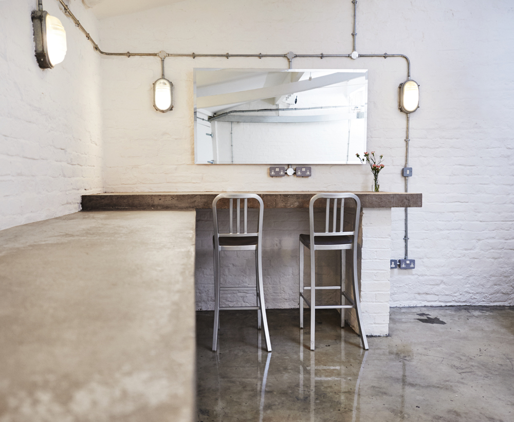 Minimalist meeting space with concrete bar and metal stools, perfect for networking events.