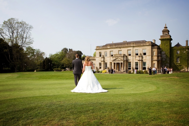 Couple walking towards Manor House, a romantic wedding venue with historic architecture.