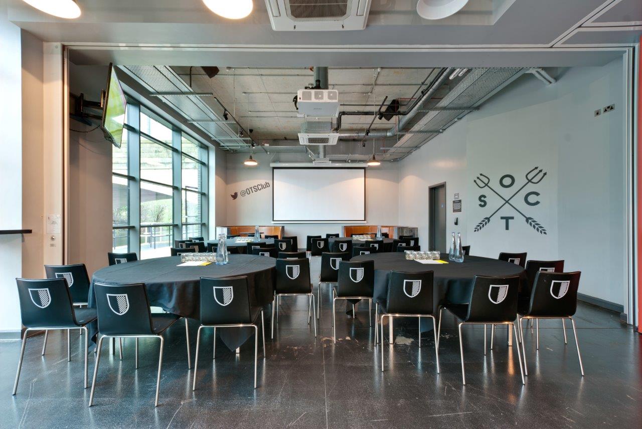 Old Trafford Supporters Club meeting space with round tables, ideal for corporate events.