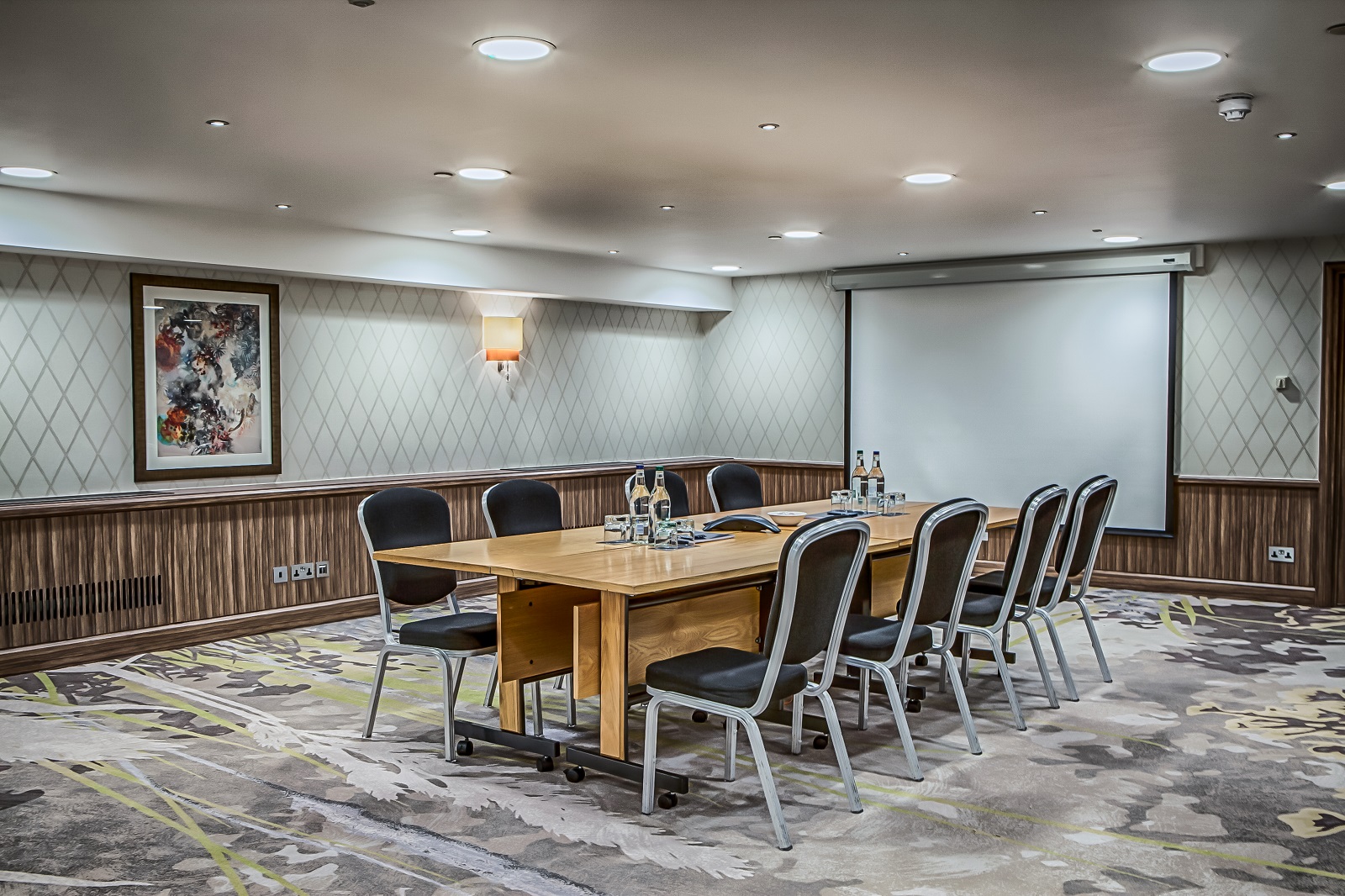 Chelsea Room at Hilton London Kensington, modern meeting space with large wooden table.