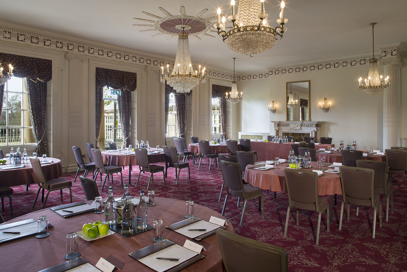 Elegant ballroom at Buxted Park Hotel for corporate events with round tables and chandeliers.