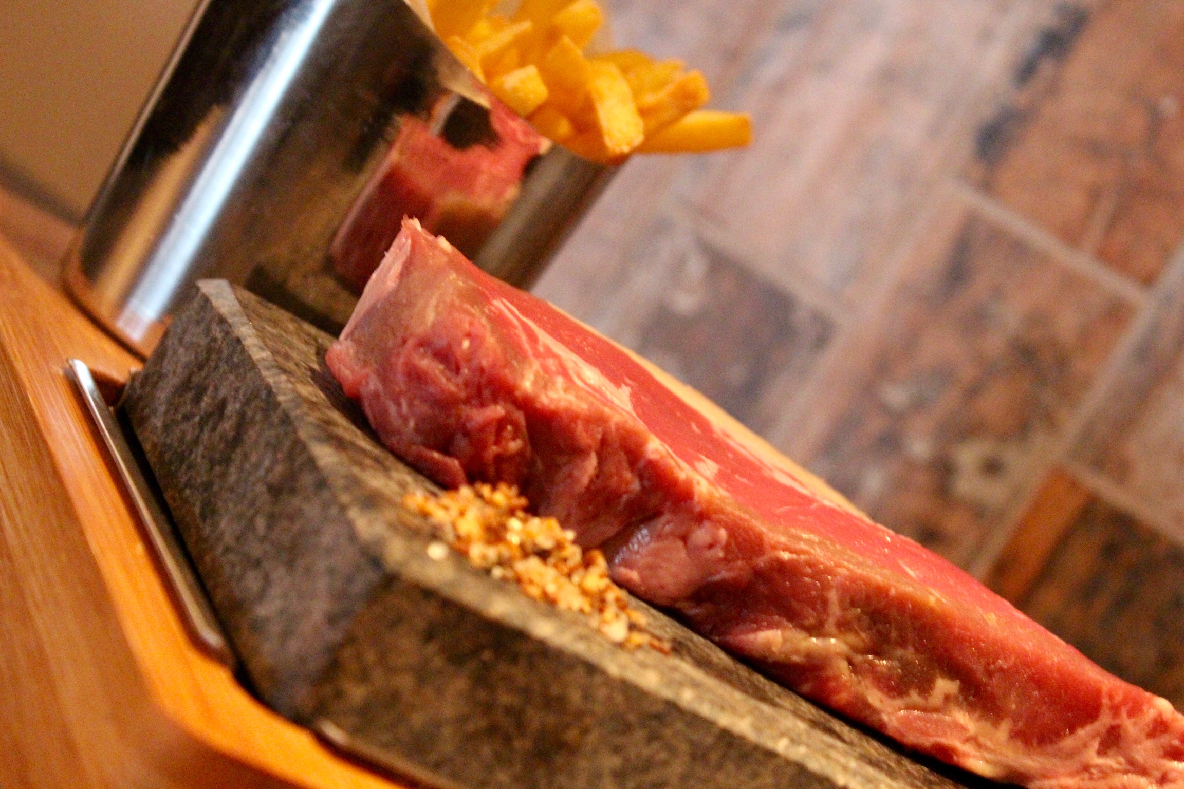 Raw steak on heated stone at upscale event venue in Suburb SW11, perfect for themed dinners.