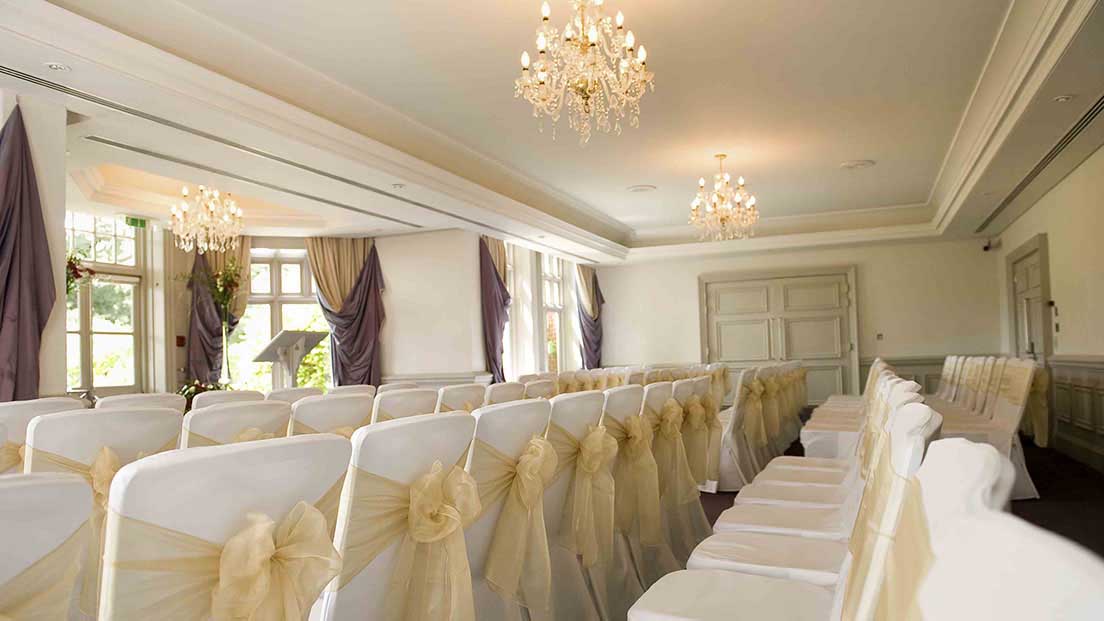 Cornwall Suite at Woodlands Park Hotel, elegant wedding venue with chandeliers and gold sashes.