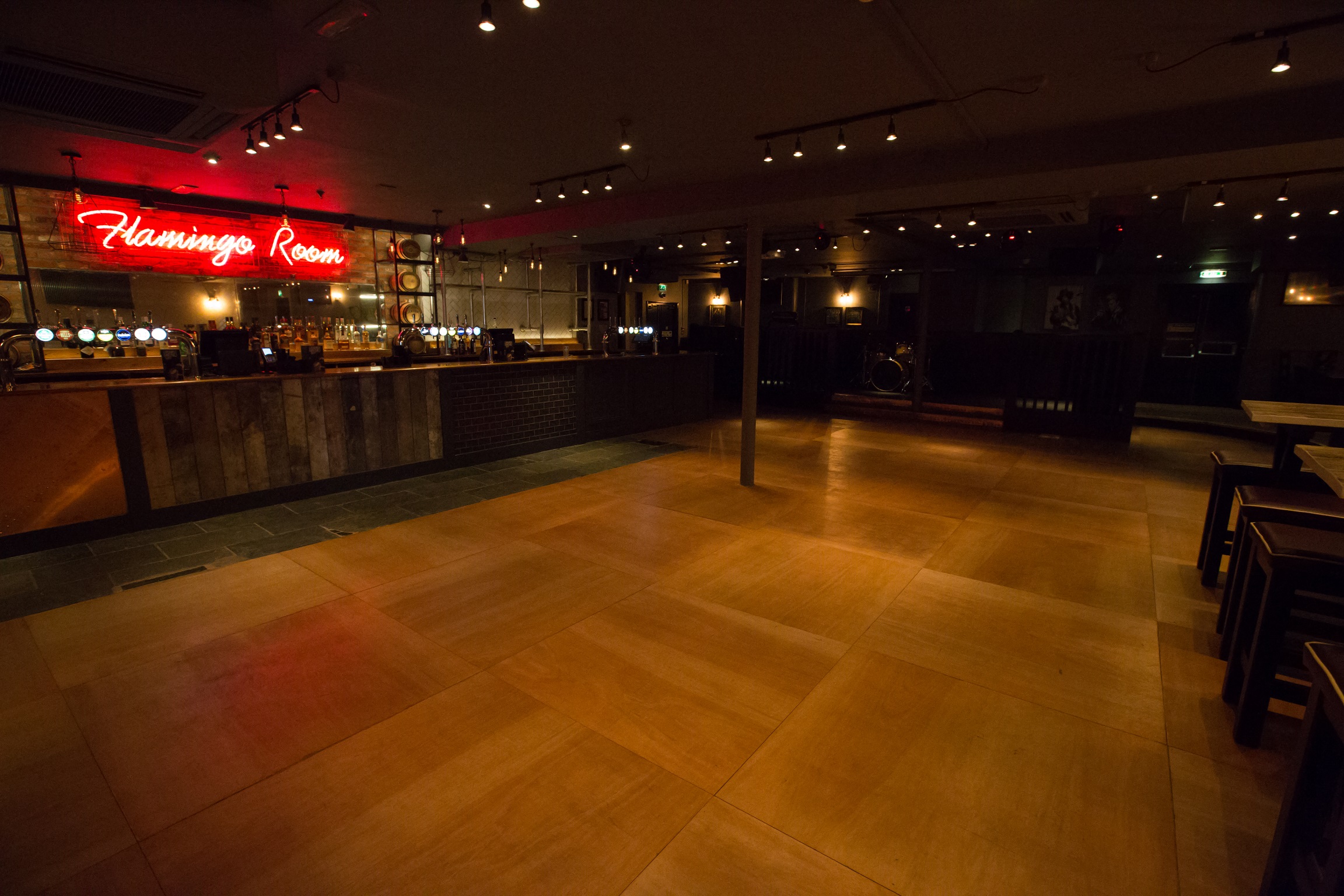 Spacious event venue with neon "Flamingo Room" sign, perfect for gatherings and parties.