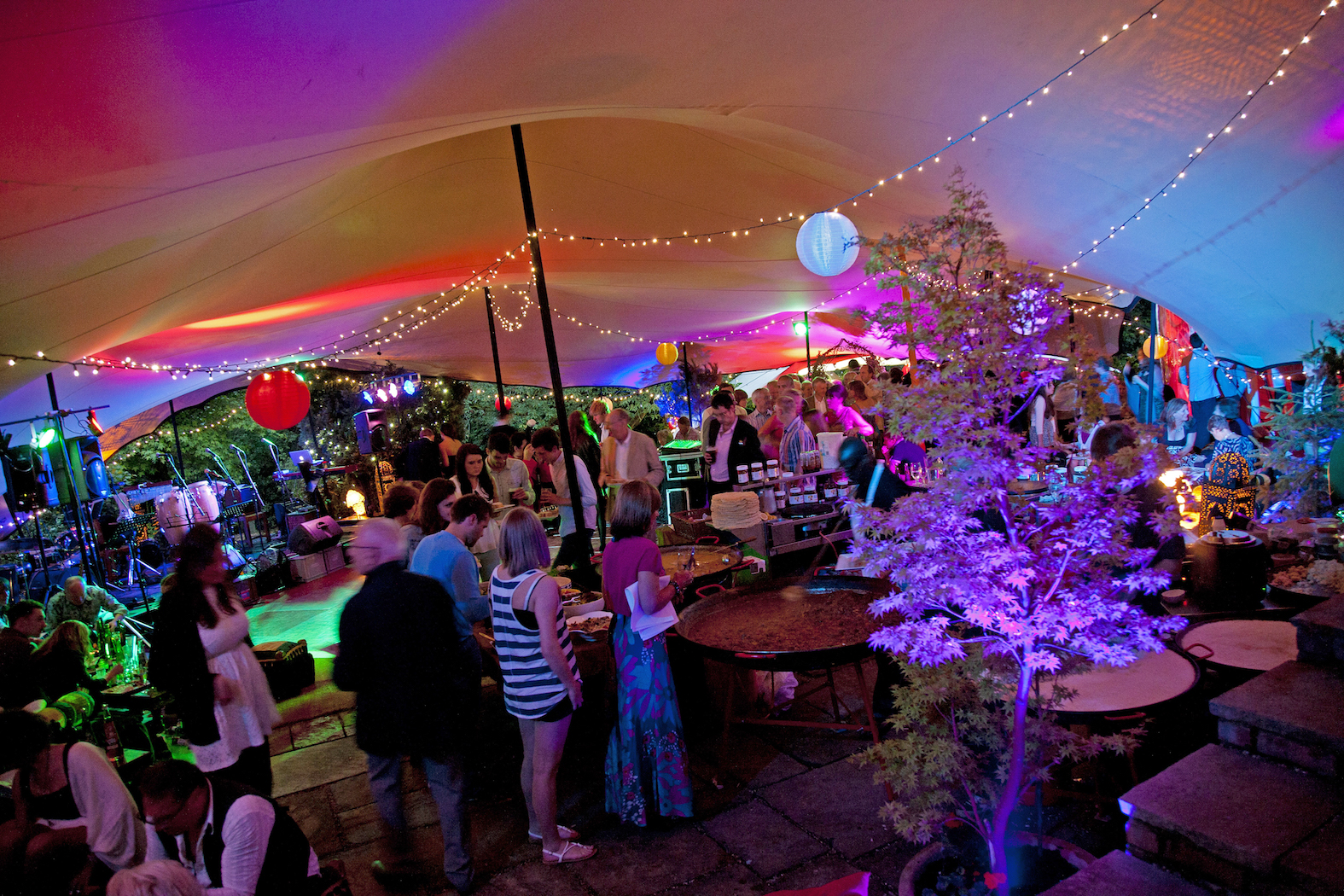 Vibrant wedding venue under a large tent with colorful lights and cozy seating.