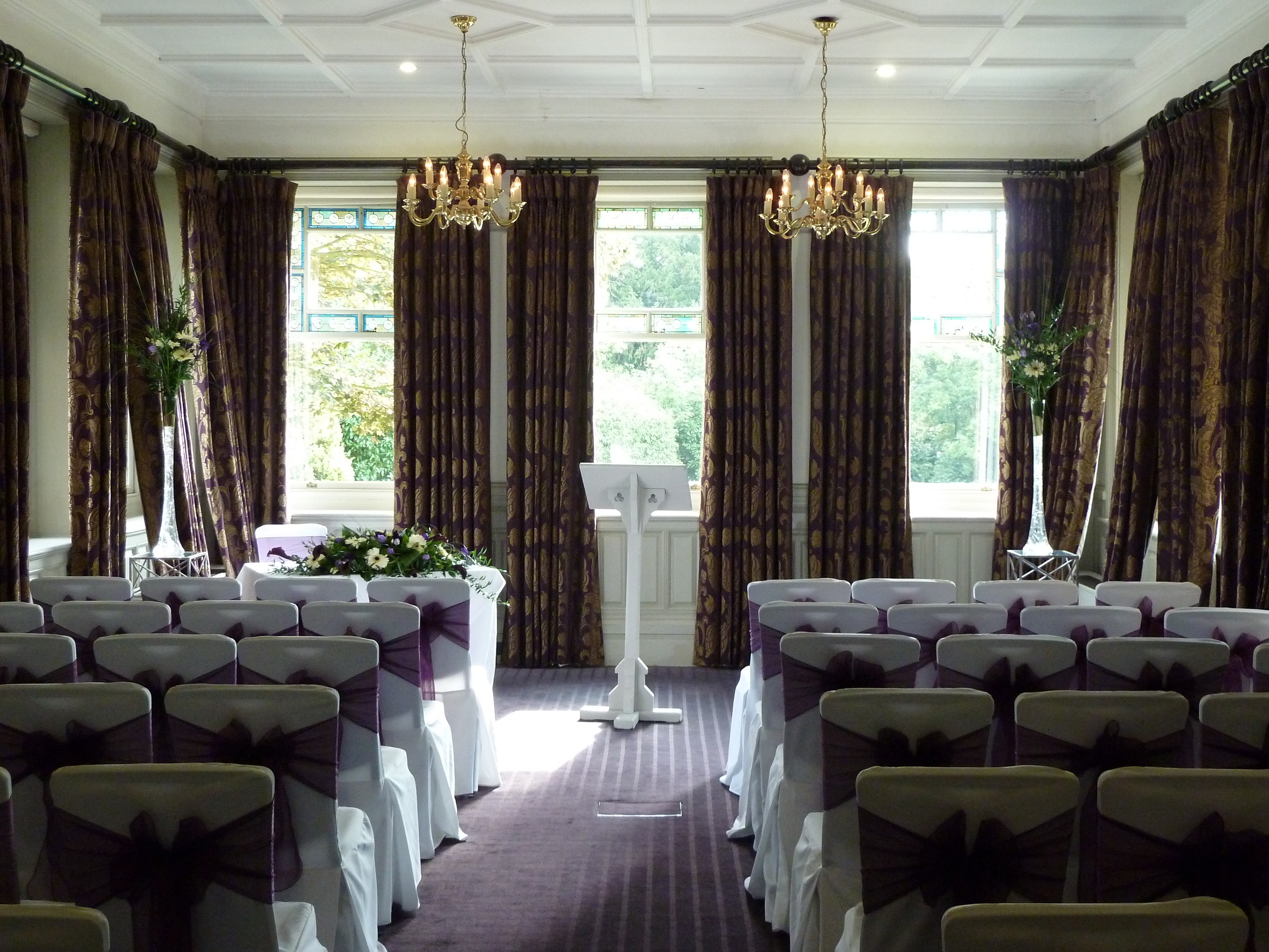 Elegant wedding venue with purple-sashed chairs and natural light at Woodlands Park Hotel.