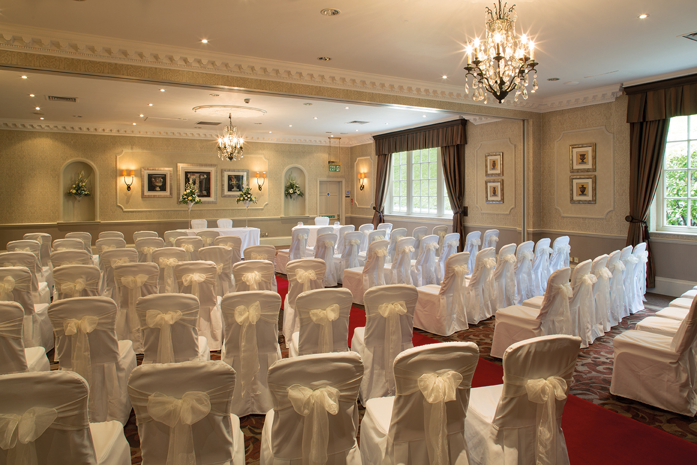 Vavasour Suite at Wood Hall Hotel, elegant wedding venue with chandeliers and red carpet.