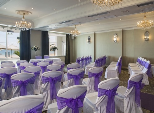 Elegant wedding setup with white chairs and purple sashes at L'Horizon Beach Hotel.