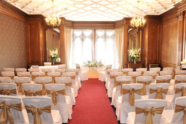 Gibson Room at Nutfield Priory, elegant wedding venue with wooden paneling and gold sashes.