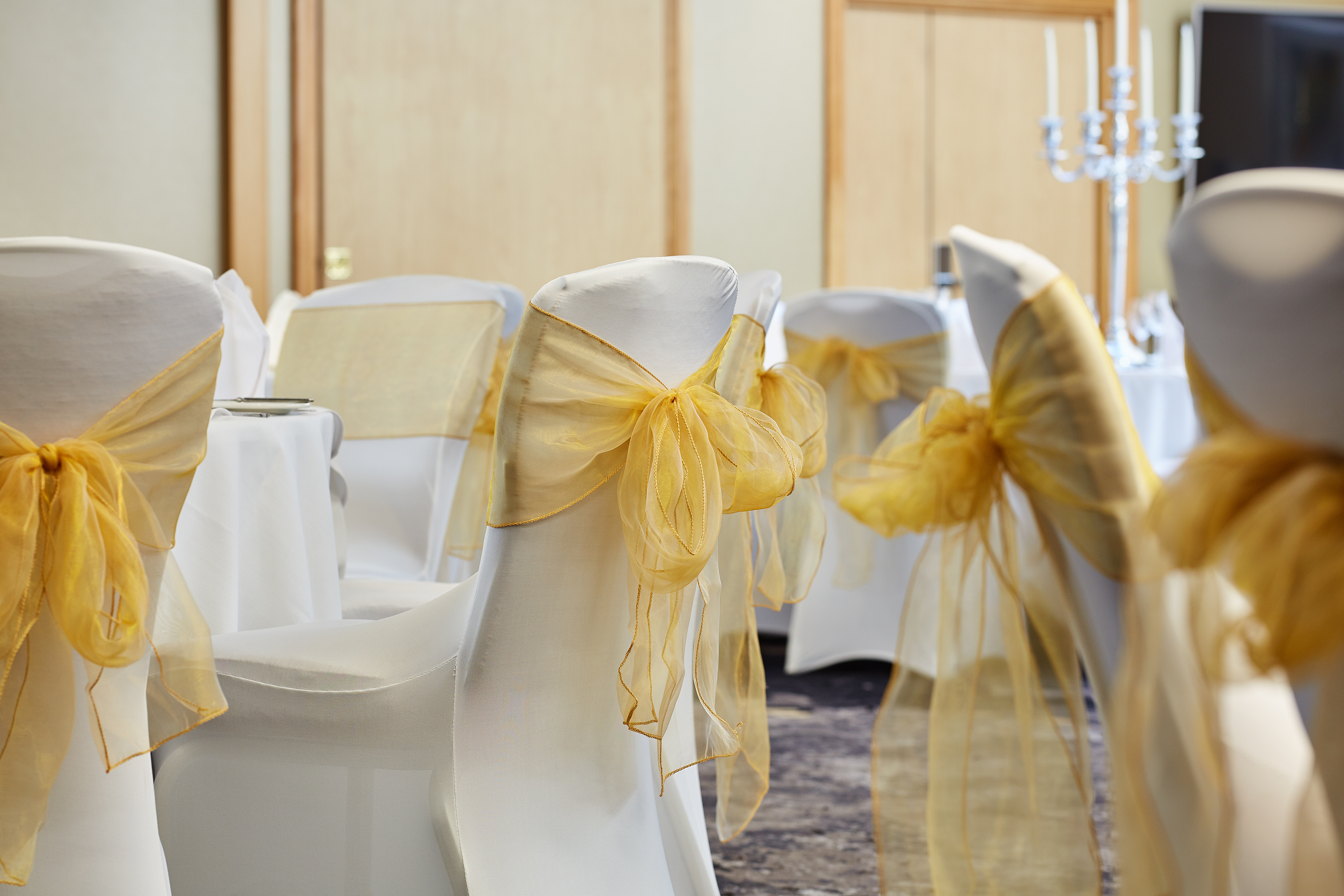 Buckingham Suite at The Bull Hotel, elegant wedding event space with white chairs and yellow sashes.