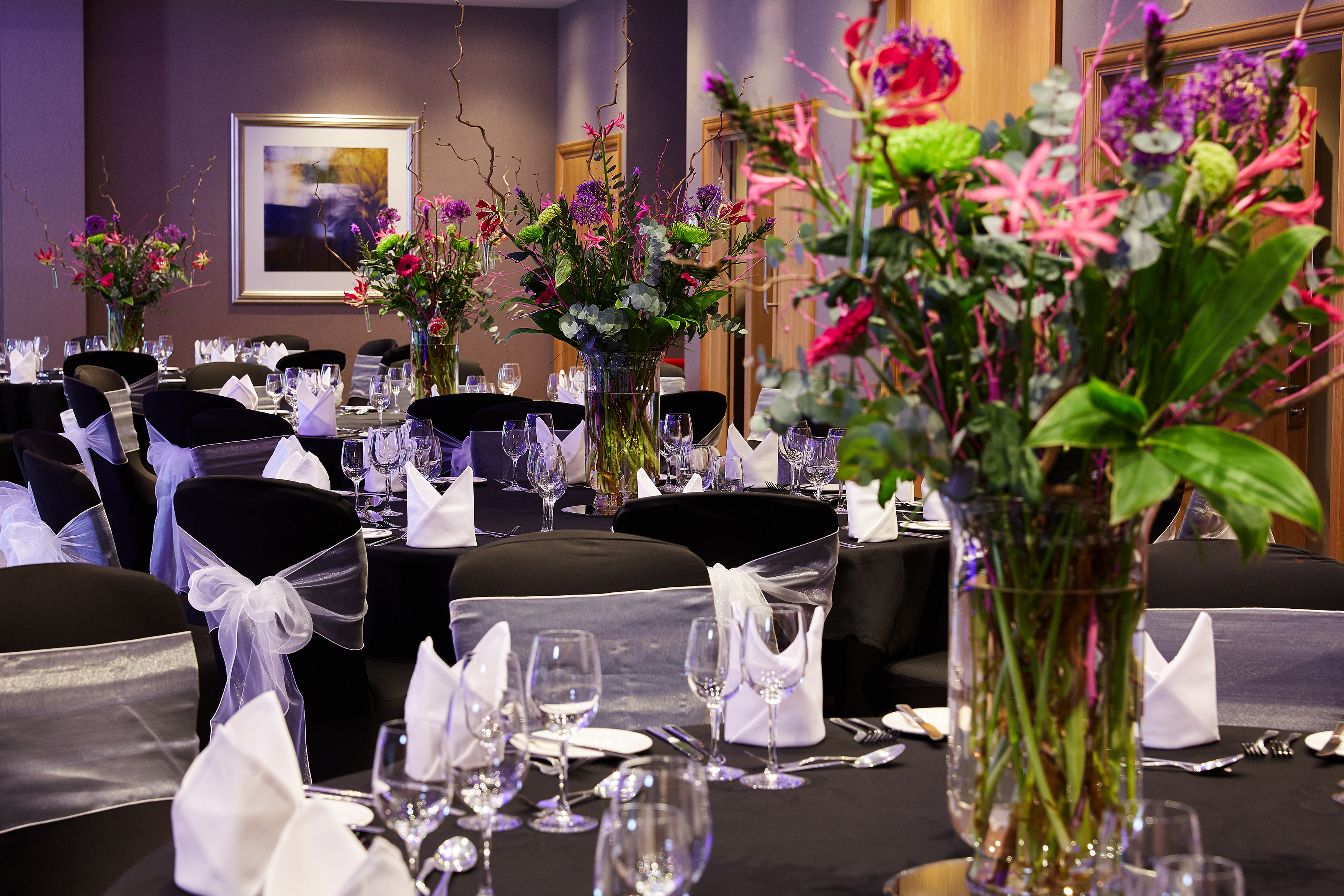 Elegant Thames Suite banquet room with floral centerpieces for formal events.