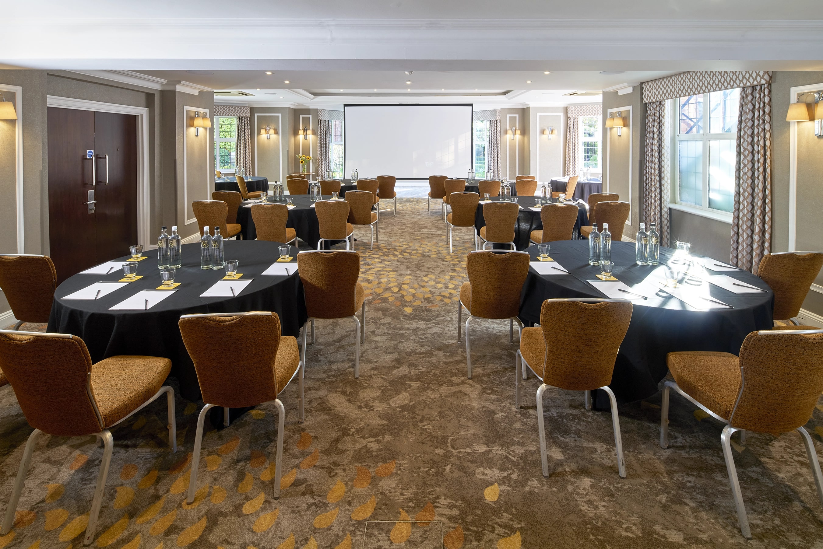 Bulstrode Suite meeting room with round tables for corporate events and presentations.