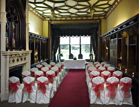 Elegant wedding venue with white chairs and red sashes at Ettington Park Hotel.