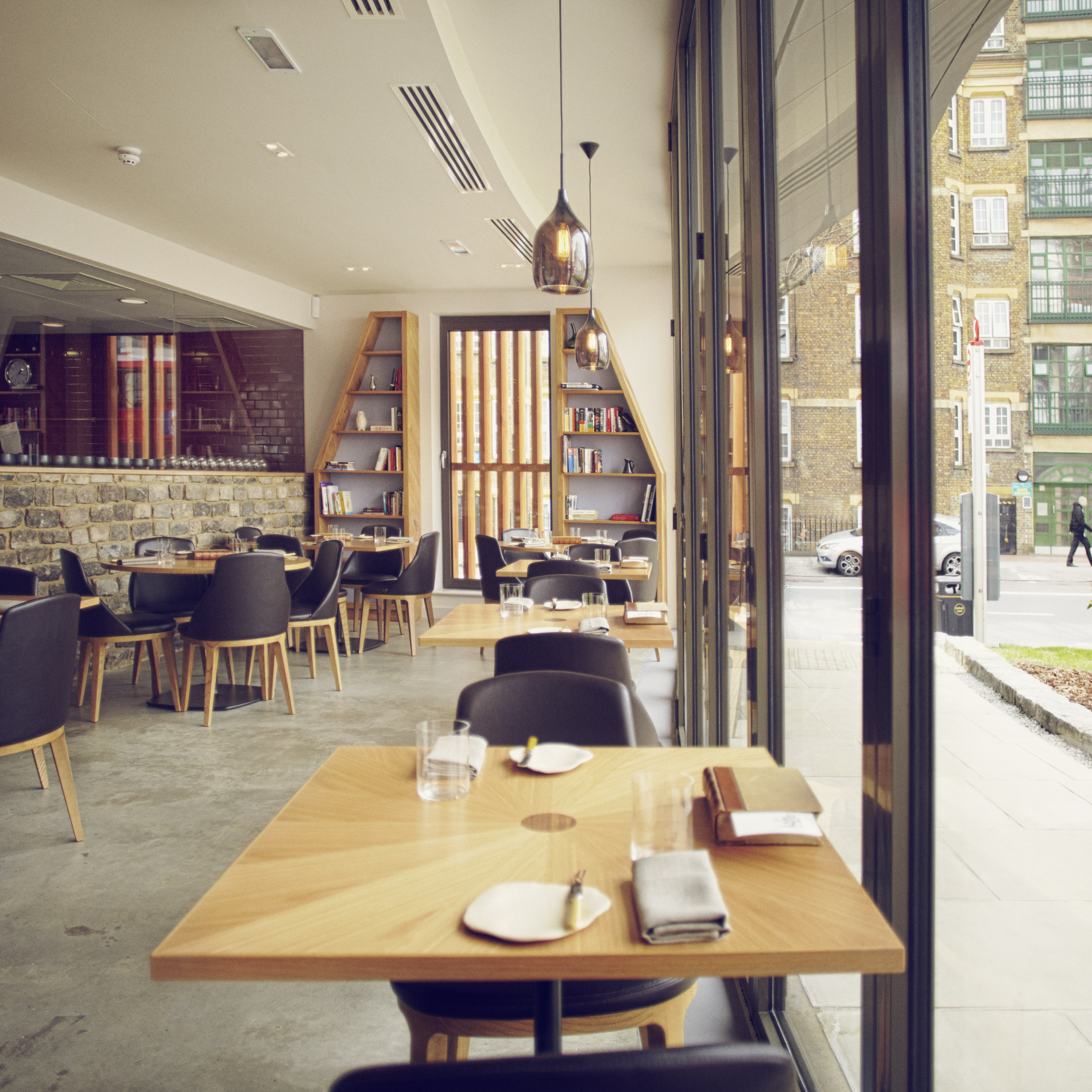 Modern restaurant interior with wooden tables, ideal for networking events and intimate dinners.