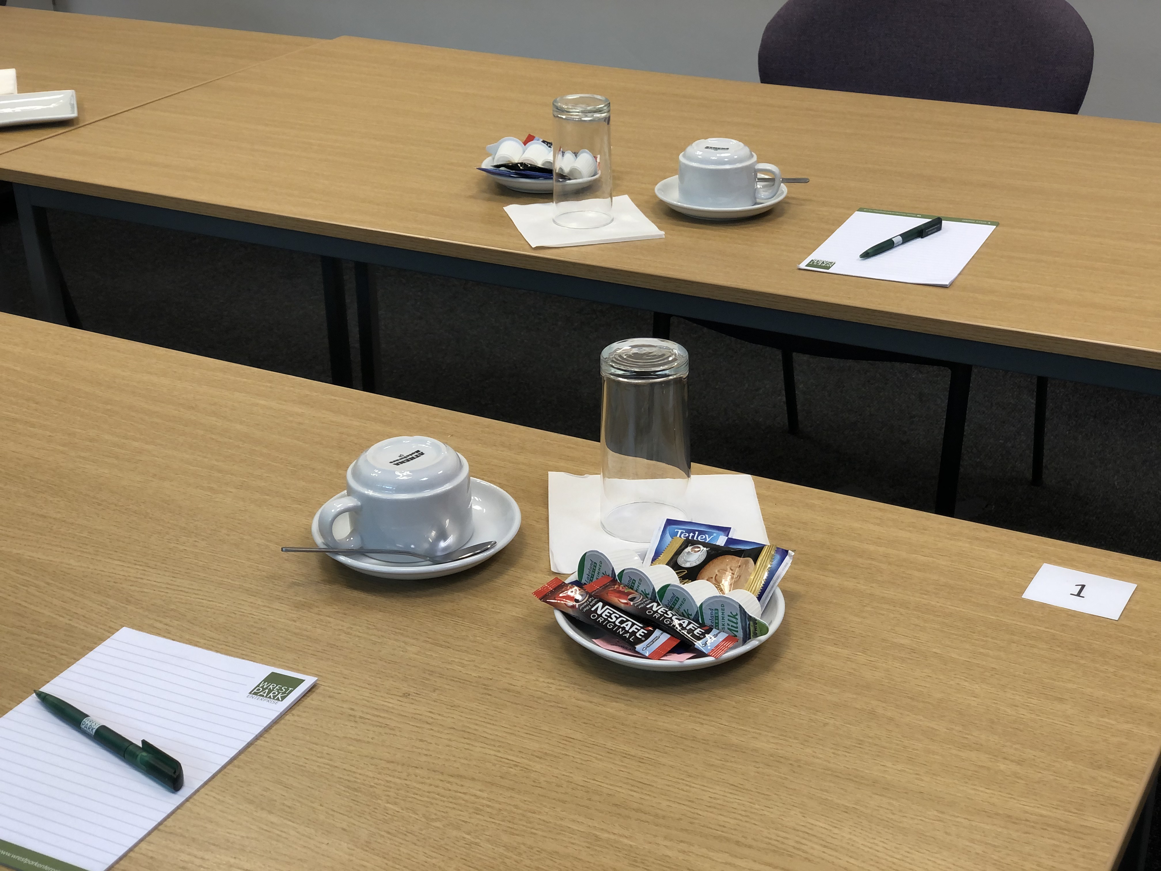 Boardroom setup at Capability House with tables, notepads, and coffee for meetings.