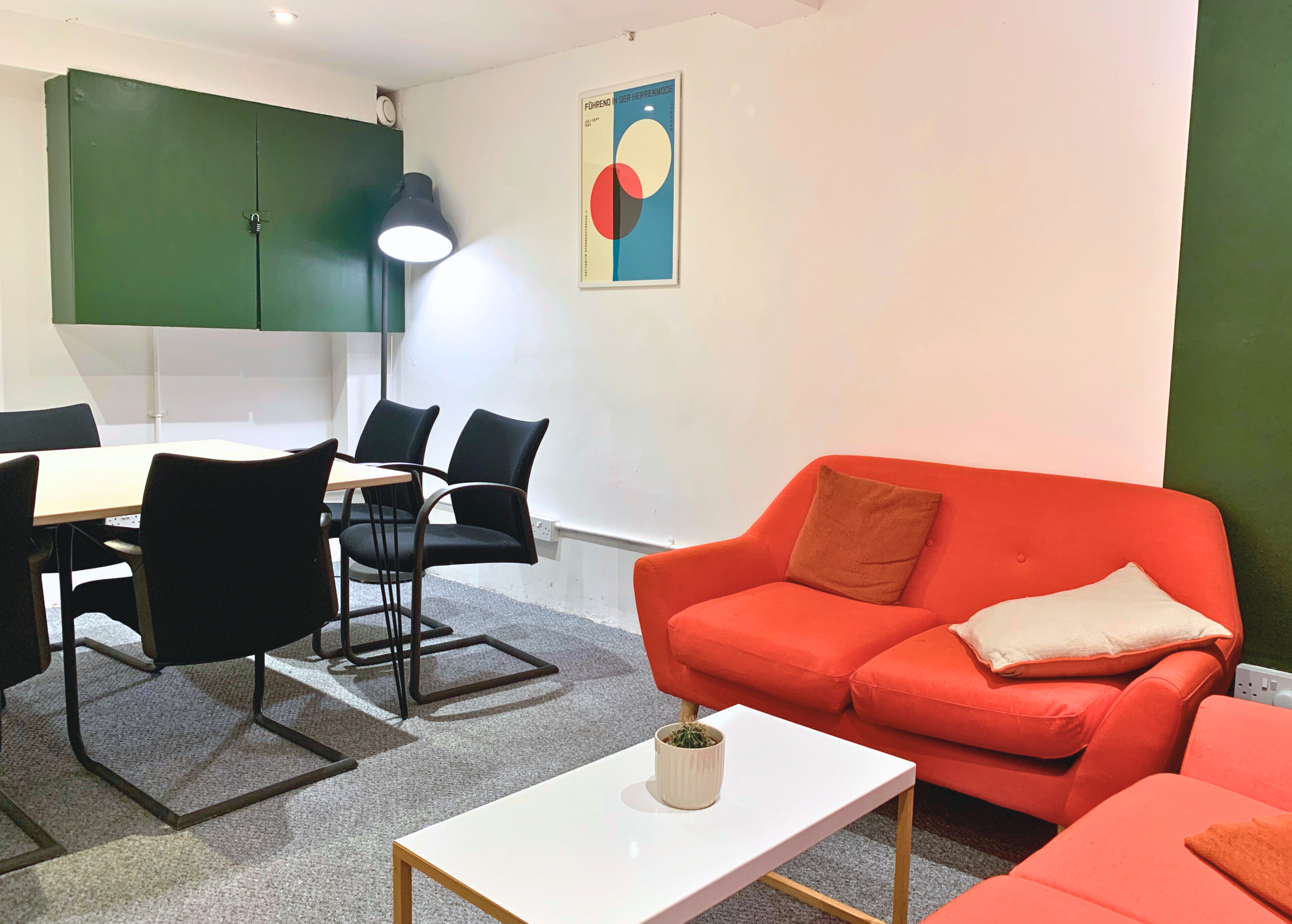 Modern boardroom in ARK coworking with vibrant orange couch for meetings and collaboration.