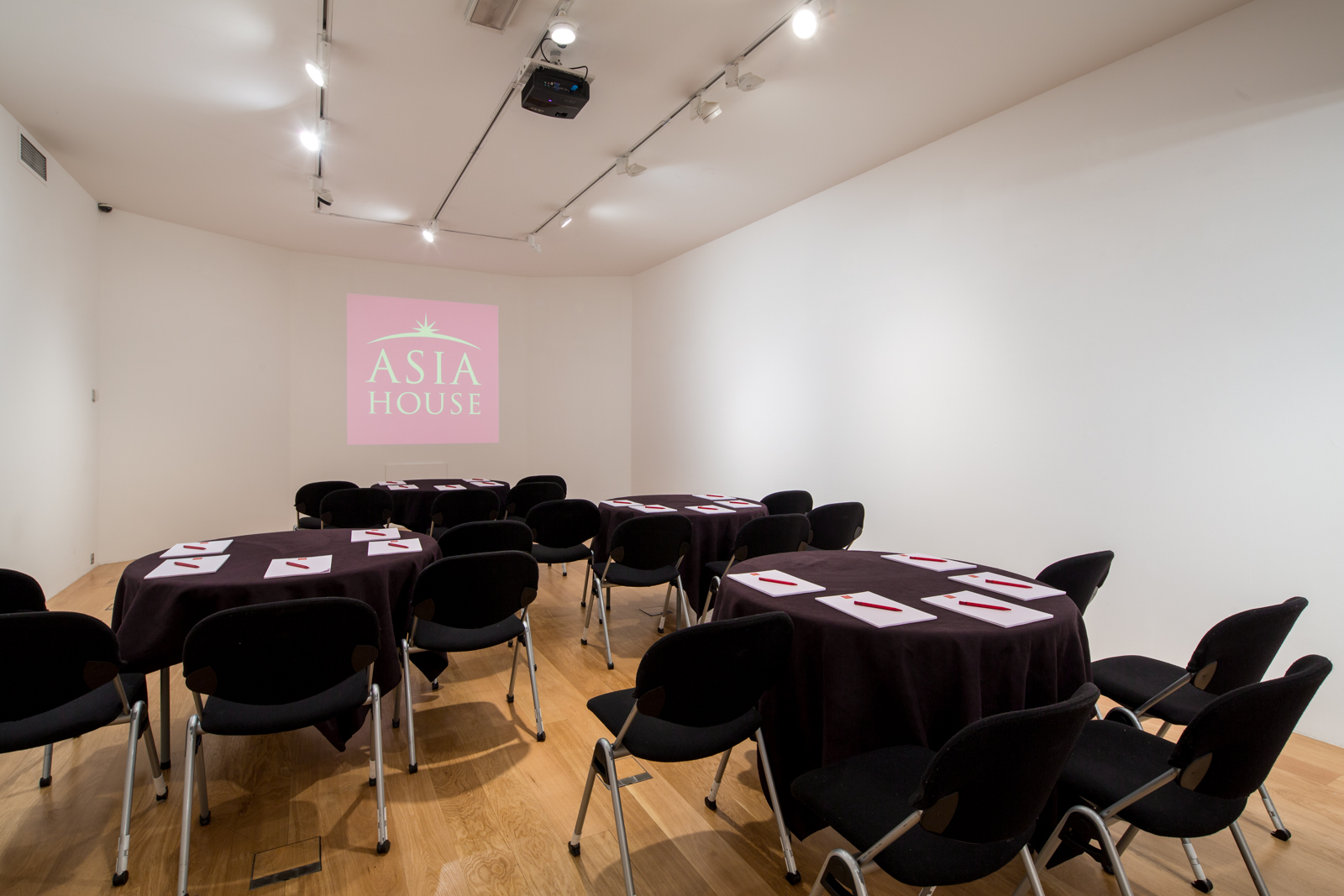 Versatile meeting space at Asia House with round tables, ideal for events and presentations.
