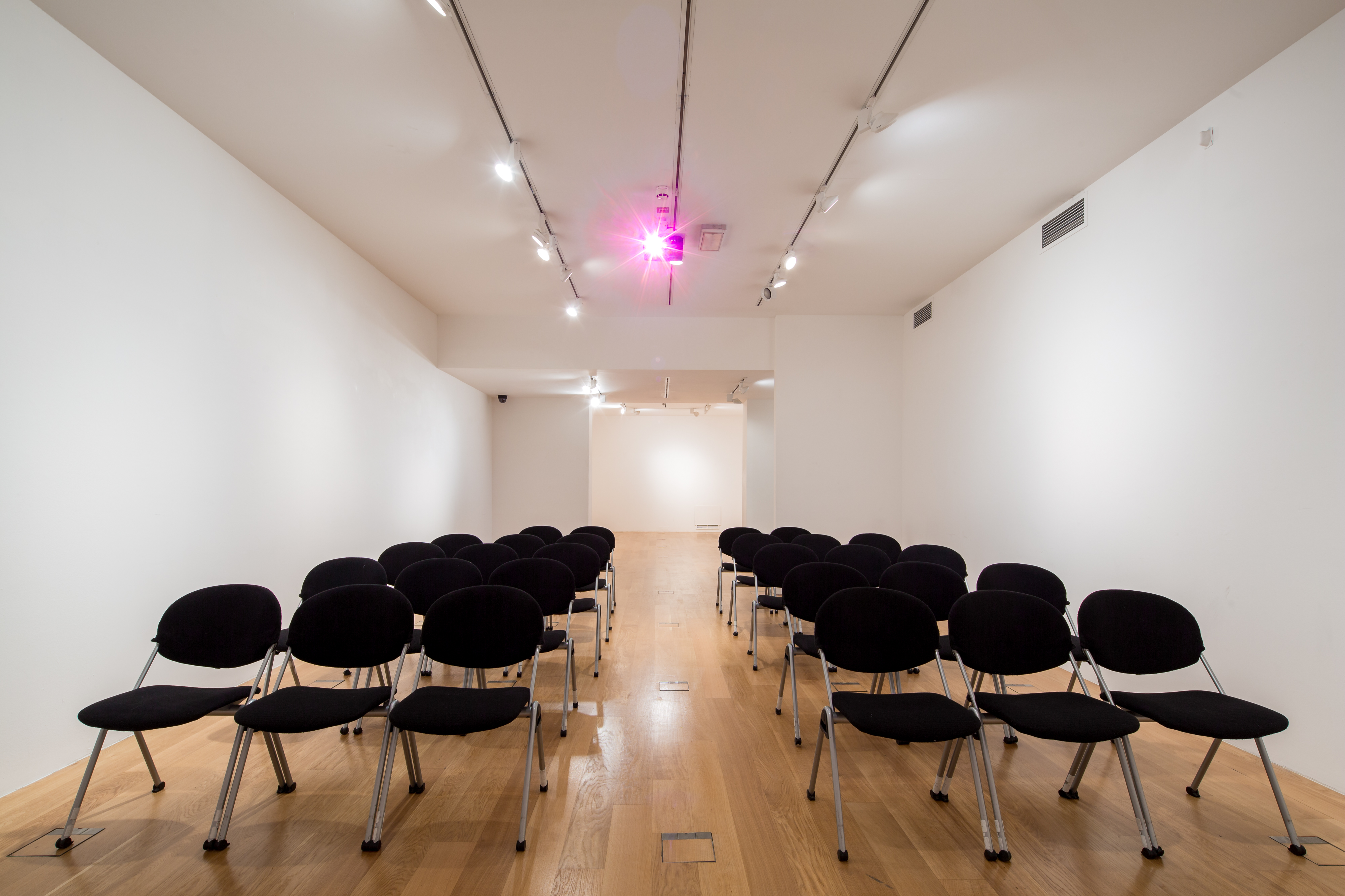 Minimalist event space in Asia House with black chairs for a seminar presentation.