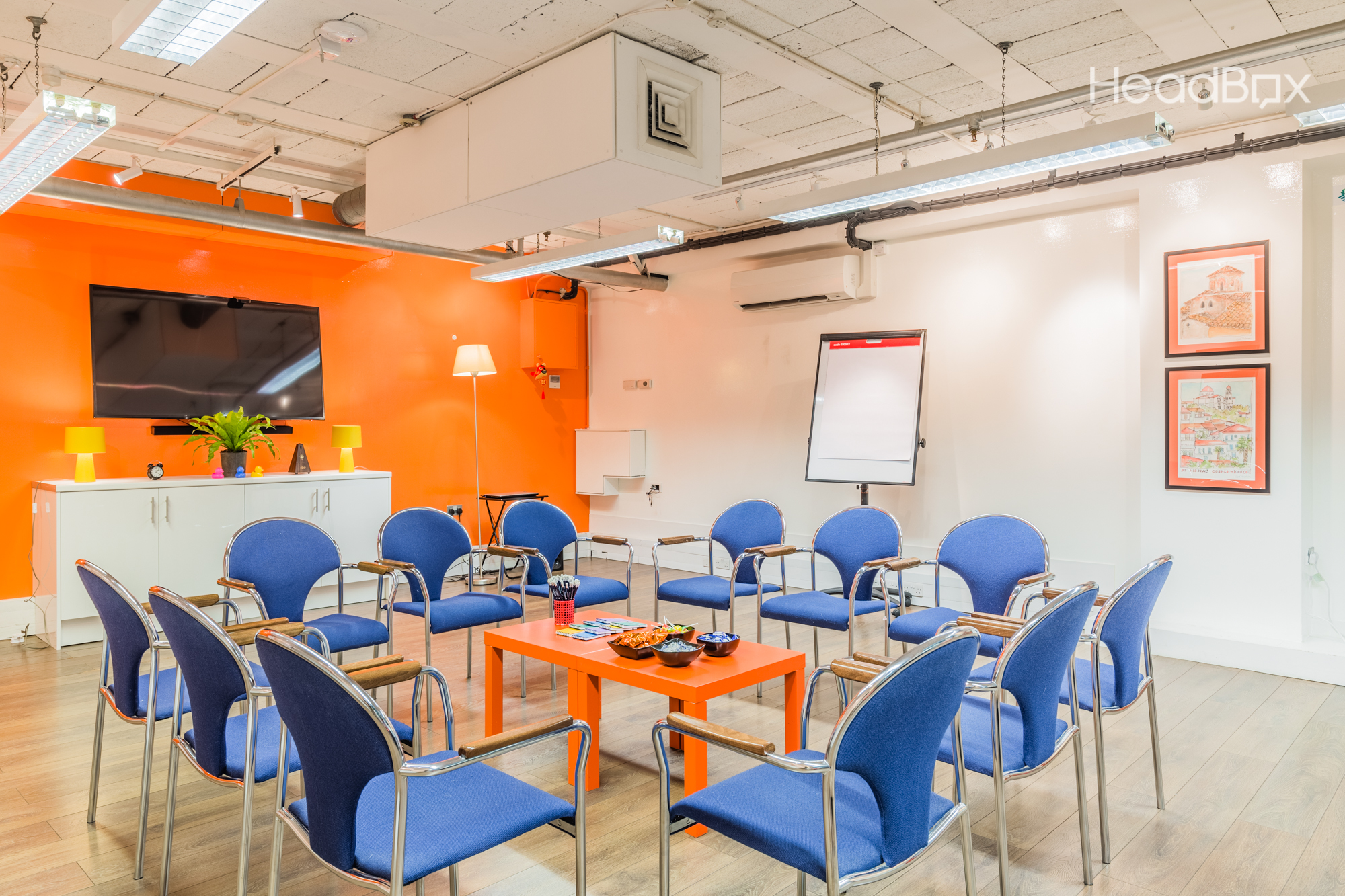 Bright Room at Impact Factory: vibrant orange wall, ideal for workshops and team meetings.