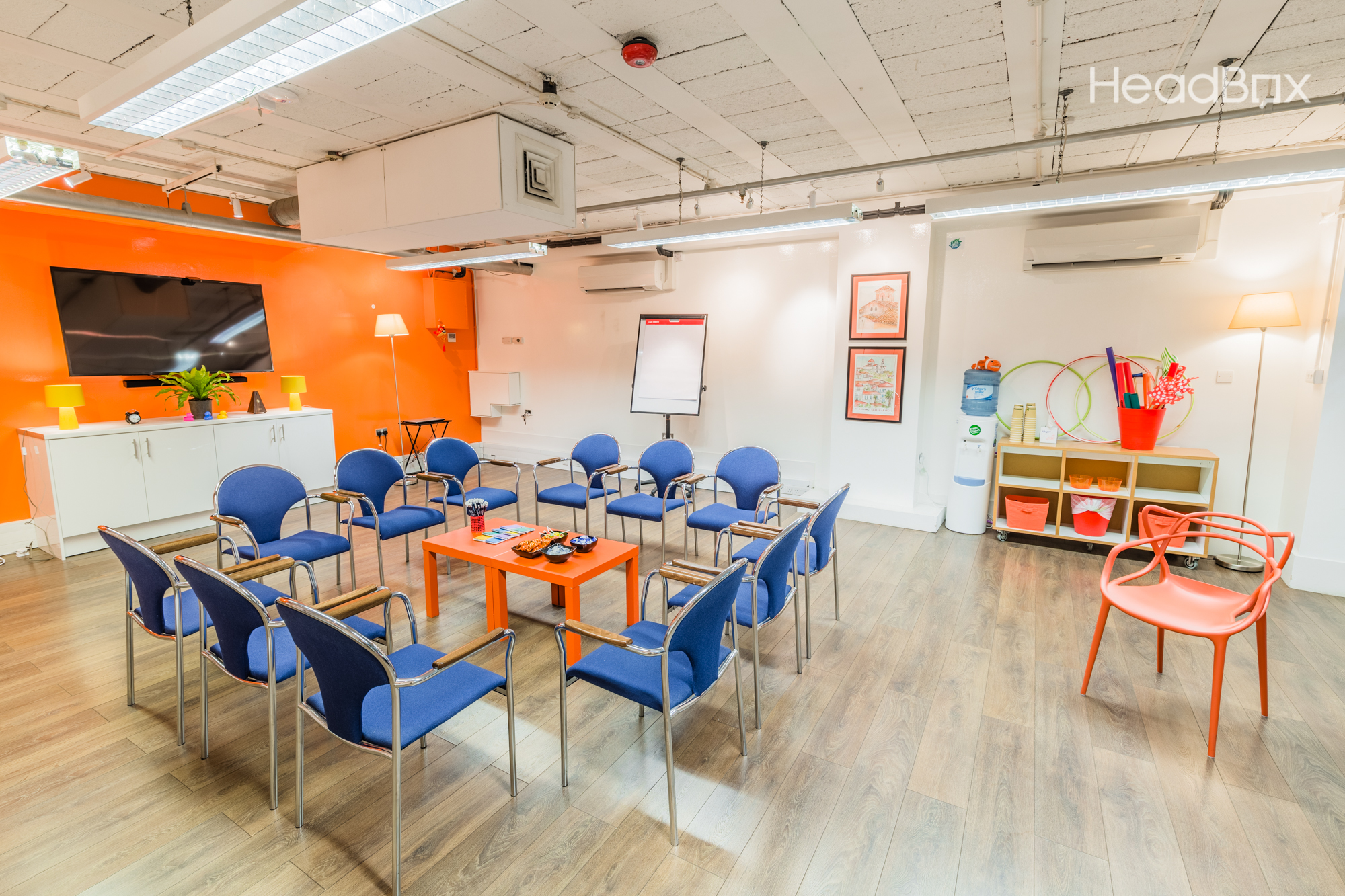 Versatile meeting space with circular seating in vibrant orange for workshops and collaboration.