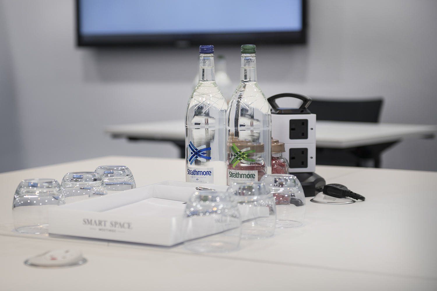 Trafalgar Suites meeting setup with water, glassware, and tech amenities for events.